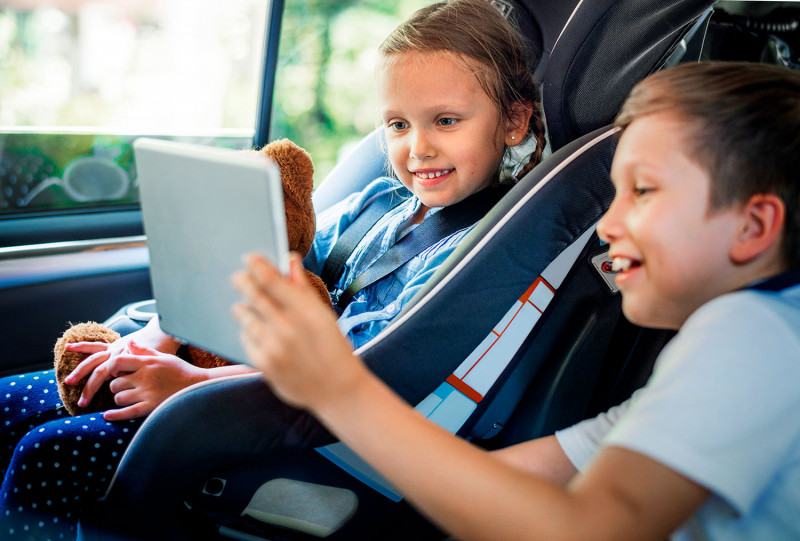 Дети в машине играют в планшете